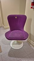 Front view of the purple egg chair showing the curved back and seat cushion with visible wear and a small stain on the chair back.