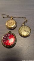 Overall view of three pocket watches and attached chain