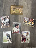 Top-down view of several 1991 NFL Pro Set trading cards laid out on a wooden floor, showing front images of players and the sleeved Raghib Ismail rookie card with gold border.
