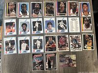 Photo of front sides of 22 basketball cards arranged in 4 rows showing player images and holographic cards of Larry Bird and David Robinson
