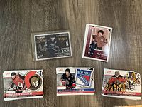 Photo showing five hockey cards laid out on wood floor, including Jaromir Jagr Etched in Time protective sleeve card and cards for Marian Hossa, Mark Messier, Roberto Luongo, plus one more.