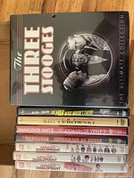 Front cover of The Three Stooges Ultimate Collection box set along with DVDs of Arrested Development seasons 1-3, The Hangover and Hangover Part II, and Coen Brothers movies The Man Who Wasn't There and The Big Lebowski.