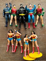 Top down view showing all 10 vintage DC Comics action figures including 3 Batman, 3 Robin, 2 Superman, and 4 Wonder Woman figures.