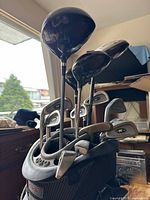 Golf bag filled with golf clubs including wooden driver and many irons.
