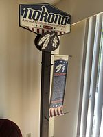 Full view of Nokona wooden coat rack featuring diamond-shaped sign and banner hanging beneath it.