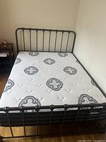 Full view of queen size black metal bed frame with Spring Air mattress on it, showing the mattress pattern and frame design.