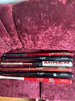 Four adult baseball bats showing wood and metal construction with brand logos and signs of minor wear.