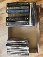 Photo of 12 DVD and Blu-ray box sets including Game of Thrones DVDs (Seasons 3 to 8), True Detective, and additional Tarantino films showing packaging condition and assortment