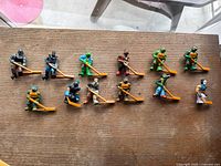 Full set of 13 TMNT table hockey figures on wooden table with orange hockey sticks and bases.