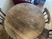 Top down view of round wooden dining table showing plank surface and wood grain with rustic finish.
