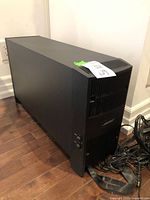 Full view of black Bose speaker unit, rectangular shape, placed on floor near wall outlet.