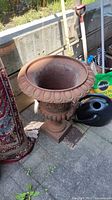Front and side view of urn planter on patio with gardening tools and mat nearby