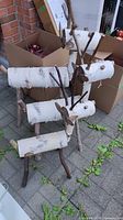 Photo showing the three birch log Christmas deer standing outdoors on a paved surface, with natural birch bark and branch legs and antlers visible.