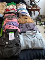 Overall view of assorted men's golf shirts laid out on bed