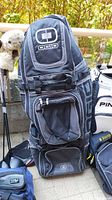 Full view of the black and gray Ogio Ohio Mammoth golf travel bag standing upright, showing multiple zippered compartments and carrying straps.
