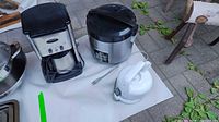 Lot items laid out on a white sheet showing the coffee maker, rice cooker, and kettle.