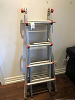 Full view of the folded metal extension ladder showing its structure, rungs, and wheels.