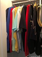 Photo of men's casual and possibly sports shirts in various colors including blue, red, yellow, black, and green