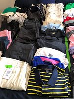 Wide view of folded polos and pants laid out on bed