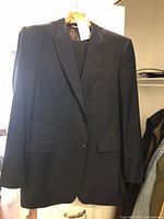 Front view of the dark Valentino men's suit jacket showing the two-button single-breasted style with flap pockets and chest pocket.