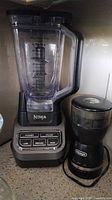Photo showing both Ninja blender and DeLonghi grinder side by side on countertop