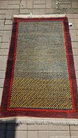 Full view of the vintage rug laid flat, showing entire patterned surface and fringed edges