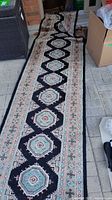 Full view of the wool blend runner rug laid out on a tiled floor, showing the length and central design with octagonal medallions and border pattern.