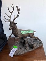 Full side view of elk sculpture showing detailed antlers and textured base