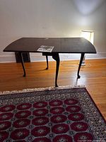 Full view of the mahogany drop leaf table with leaves outward, showing the curved legs and tabletop.