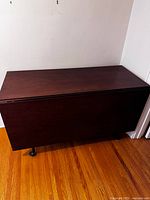 Photo of the mahogany drop leaf table folded with both drop leaves closed, showing the flat top surface and cabriole legs.