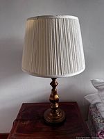 Full view of the antique brass lamp with pleated white lampshade, showing overall shape and condition