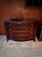 Front view of the antique mahogany dresser showing four drawers and some damage on the surface.
