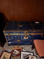 Photo of closed blue antique metal trunk with brass locks and reinforcement straps.