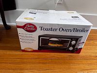 Front view of the Betty Crocker Toaster Oven/Broiler box on floor with clear product image.