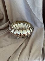 Top angled view of the silver scalloped bowl showing smooth polished surface and rounded disc shape