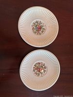 Top side view of two white china plates with ribbed edges and central floral patterns.