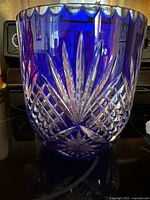 Side view of blue lead crystal vase with detailed cut patterns and scalloped rim