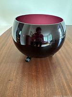 Side view of the large round purple glass bowl showing its reflective exterior and small knob base