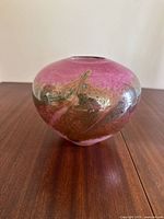 Front angle of pink and gold handcrafted glass bowl showing unique swirling design with gold accents.