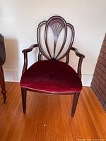 Full frontal view of antique Hepplewhite chair showing red velvet seat and mahogany wood with carved shield back and fan motif.