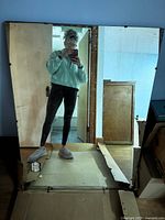 Photo showing one large rectangular mirror standing upright with a person reflection visible.