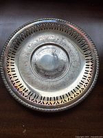 Photo of ornate round plated silver tray with pierced edge and engraved floral/scrollwork design.