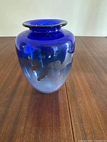 Front side view of blue glass vase with gold leaf.