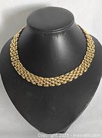 Full view of gold-tone metal chain link necklace displayed on black jewelry bust showing the layered chain link design.