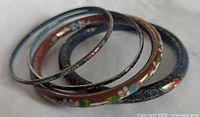 Set of four multicolor cloisonné enamel bangle bracelets showing varied floral patterns and colors including blue and red backgrounds.