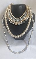 Front view of five faux pearl strands on display bust showing mixed colors and bead sizes.