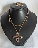 Front view of necklace displayed on black bust with matching earrings placed above.