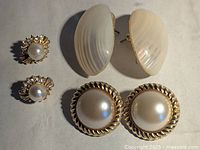 Photo showing three pairs of vintage faux pearl and shell motif earrings; includes cream shell-shaped posts, round faux pearl in twisted gold-tone setting, and gold-tone with faux pearl and rhinestone top.