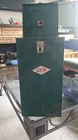 Green metal carrying case for Coleman lantern with latch and Coleman logo