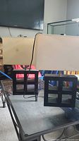 Photo showing both matching table lamps with rectangular cream shades and black geometric wooden bases on a glass table.